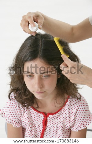Mother treating daughter's hair against lice 