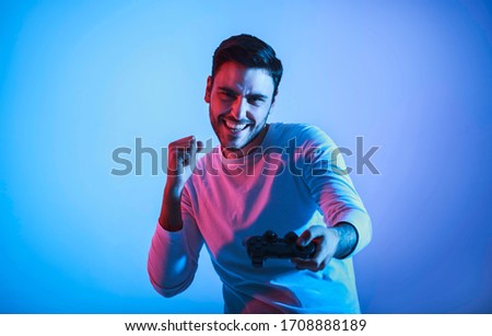 Winning at computer game. Joyful young man with gamepad, free space