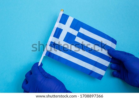 hands in blue latex gloves with Greek flag isolated on blue, coronavirus, illness, infection, quarantine,