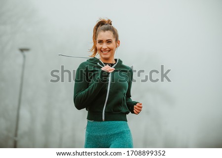 Close photo of pretty sporty woman jogging outdoor on foggy morning.