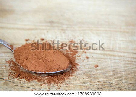 metal silver spoon wood wooden desk table loose powder powdered cocoa dry plant heap pile stack ground raw ingredient cacao sweet chocolate dust background front view