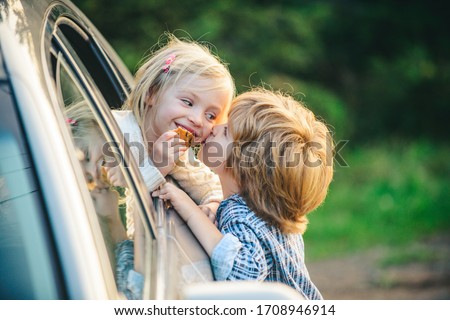 Delighted happy smiling little girl says goodbye to little boyfriend who sails for long time. Gives warm kiss. Couple saying goodbye before car travel
