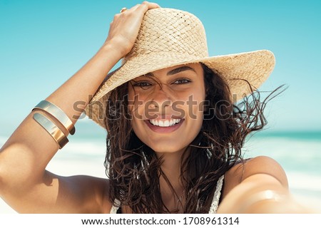Close up face of happy young woman with straw hat enjoying her summer holidays. Portrait of beautiful latin girl relaxing at beach and looking at camera. Carefree brunette beauty woman enjoy summer.