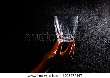 Clean glass in a hand. Spray on a glass of water.  