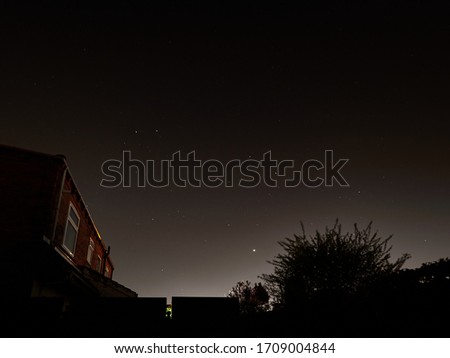 The planet Venus low on the horizon and stars sparkle clearly on a cloudless night over houses on a street in Wakefield, Yorkshire.