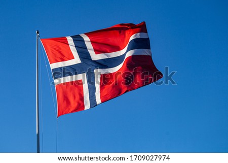Norwegian flag in sunshine on clear blue background