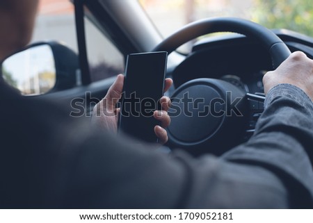 Mockup of man driver hand using blank black screen mobile smart phone while driving a car, searching location via gps navigator application, close up