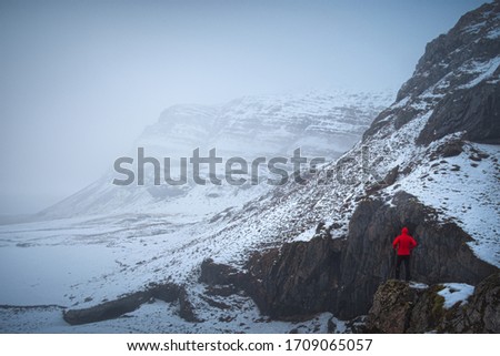 A man at the top of a rock in a full of snow landscape in Iceland.