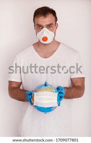 Man is holding globe in medical mask. Covid concept.