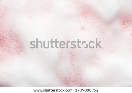 White cosmetics foam texture on pink backdrop. Cleanser, soap, shampoo bubbles. Foamy skin care product sample. Skincare, cosmetology and beauty concept Royalty-Free Stock Photo #1709088952