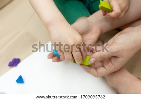 Mom and child knead multicolored plasticine. hands closeup. children's creativity. crafts in kindergarten, school.