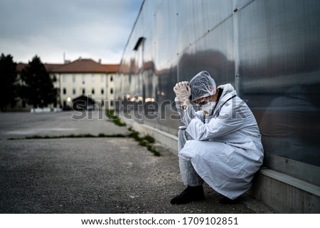 Frightened doctor for infectious diseases having mental nervous break down.Coronavirus COVID-19 exhausted physician in fear.Working in improvised medical facility isolation ward.Medical worker stress Royalty-Free Stock Photo #1709102851