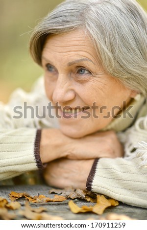 Senior smiling woman sitting outdoors at table in autumn