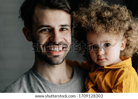 father and daughter. Young pretty dad and his little curly daughter hugging and having fun at home
