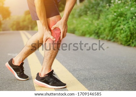 Runners leg pain, man holding sore and over trained painful leg muscle or cramp .Injured over trained person when exercising or running jogging outdoors. Royalty-Free Stock Photo #1709146585