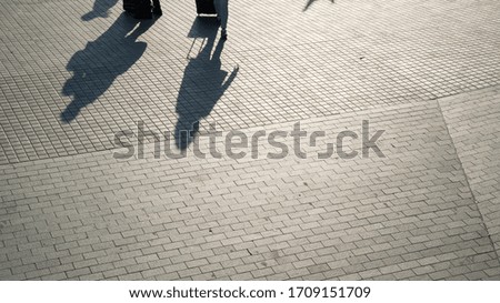 Urban scene. Silhouettes of people and shadows on the earth. Shadows on the street tiles. Bright sun and contrasting shadows. City walks. Urban lifestyle.