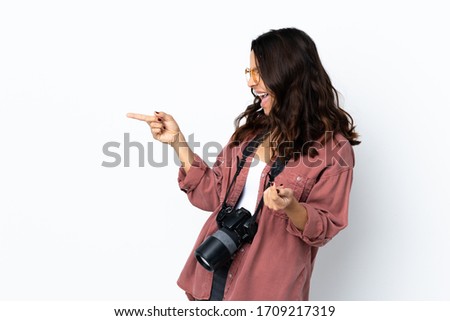 Young photographer woman over isolated white background pointing finger to the side and presenting a product