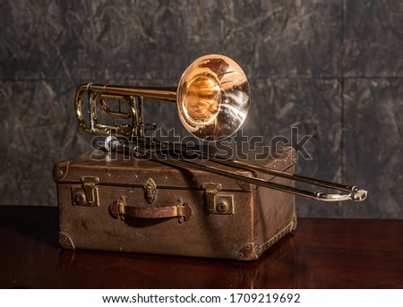 Golden trombone musical instrument lies on an old suitcase Royalty-Free Stock Photo #1709219692