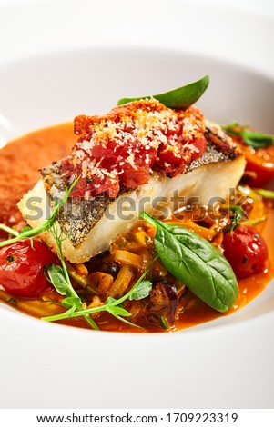Halibut steak in crispy breading close up. Served cuisine. Dish with fish fillet and zucchini spaghetti in tomato sauce in white plate isolated. Restaurant food portion, delicious supper, main course