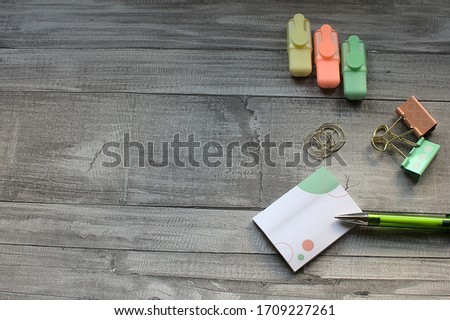 Negative space, concept work at home. notepad and green pen, next there is paper clips and highlishters, on wooden table