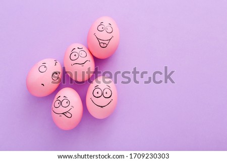 Funny pink eggs with face feeling on purple background