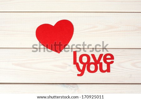 Heart symbol cut out paper on a wood background with inscription  love you