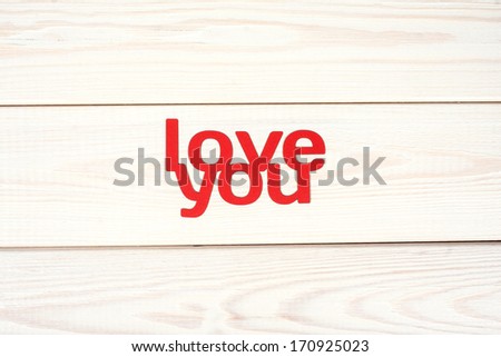 Words love you carved out of red paper on a wooden background