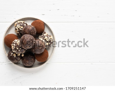 Energy balls. Healthy raw dessert (bliss balls), vegetarian truffles, sugar free candies made of dates, hazelnuts, cocoa powder. Step by step cooking. White wooden background.  Royalty-Free Stock Photo #1709251147