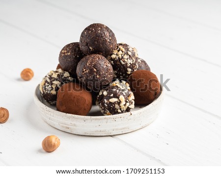 Energy balls. Healthy raw dessert (bliss balls), vegetarian truffles, sugar free candies made of dates, hazelnuts, cocoa powder. Step by step cooking. White wooden background.  Royalty-Free Stock Photo #1709251153