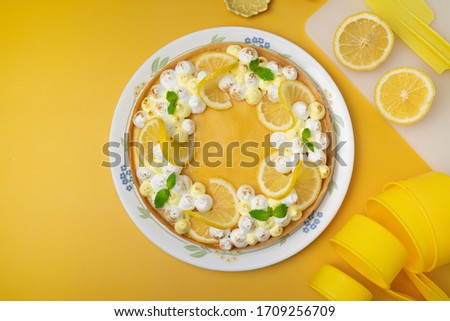 Lemon tart decorated with white meringue and mint leafs - yellow background with copy space