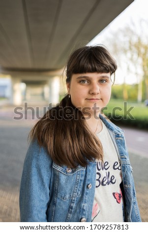 A caucasian girl wearing a blue jeans jacket