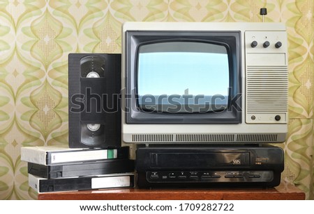 Old silver-colored TV with a VCR on the background of wallpaper.Screen noise. Royalty-Free Stock Photo #1709282722