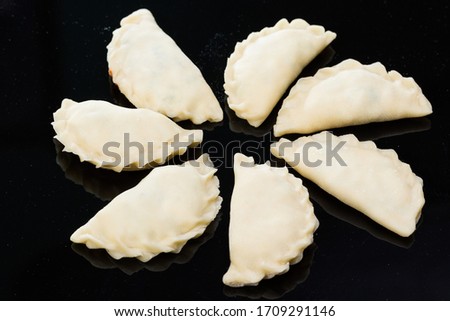 Semi-finished dumplings mantas on a black background lying in a circle Royalty-Free Stock Photo #1709291146
