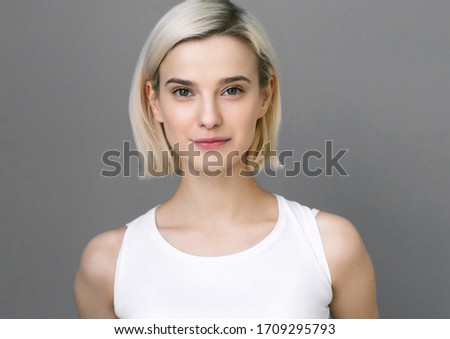 Beautiful woman natural young female short blond hair over gray wall