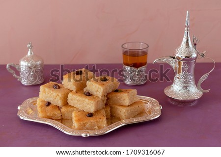 Basbousa is a traditional sweet dessert or semolina pie with a glass of tea. Ramadan food. Royalty-Free Stock Photo #1709316067