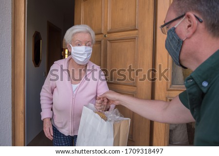 Senior woman gets shopping bag from neighborhood assistance Royalty-Free Stock Photo #1709318497