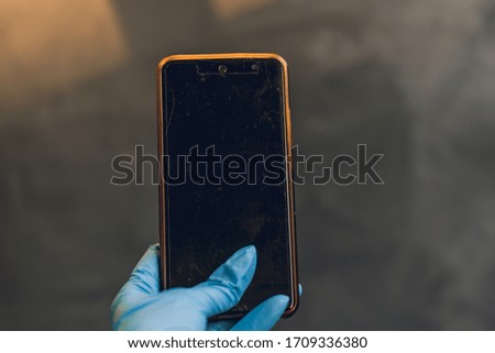 medical mask and blue nitrile medical gloves with a smartphone for remote work on a gray heterogeneous background