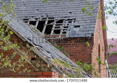 Damaged slate roof tiles on a pitched roof on a derelict house Royalty-Free Stock Photo #1709351488