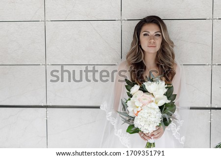 Beauty Portrait of bride wearing in wedding dress with voluminous skirt, studio photo. Young attractive bride with bouquet of flowers. Smiling beautiful young bride