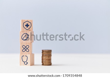 Health insurance. Healthcare and medicine concept. Stack of wooden cubes with medical signs, pile of coins, copy space