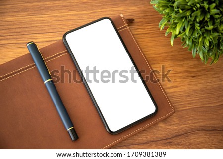 phone with isolated screen on table with notebook and pen in the office