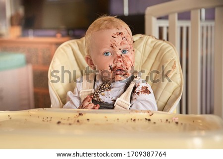 Portrait of a little boy with a birthday cake. Birthday at home alone.Chocolate-smeared face. No guests.