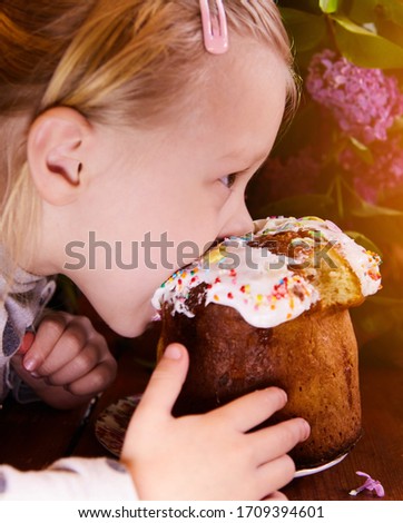 One child girl eats an Easter cake. Bites the delicious icing sugar.