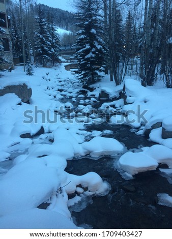 frozen river in colorado sprinkled with powdery snow trees in the picture also