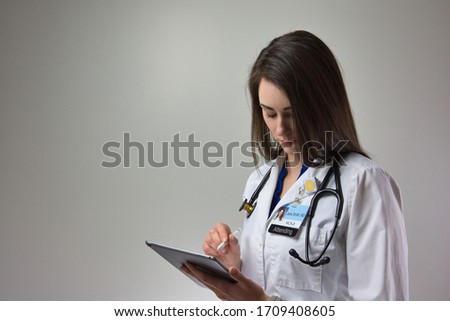 woman making note on tablet for patient care in hospital. Healthcare female, could be MD, PA, or NP