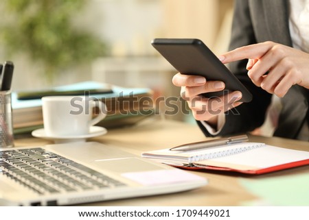 Close up of entrepreneur woman hands with agenda using smart phone on a desk Royalty-Free Stock Photo #1709449021