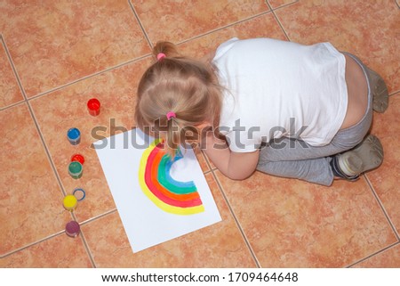Kid painting rainbow at home during coronavirus pandemic concept. Let's all be well. Stay at home Social media campaign. Children Chase the rainbow