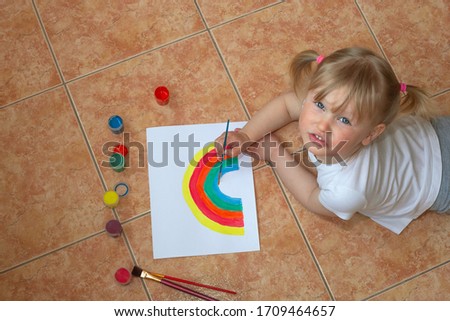 Little girl drawing rainbow. Sign of hope during coronavirus outbreak. Quarantine fun. Arts and crafts for kids. Kids paint. School kid doing art homework.