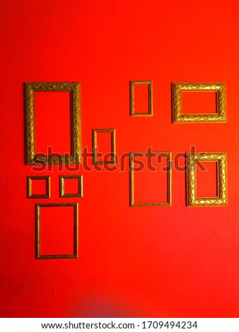 Various rectangular gold picture frames with red background.