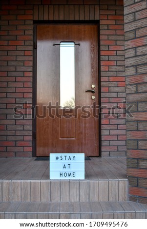Stay at home' words on lightbox, near the house entance door. Copy space. 